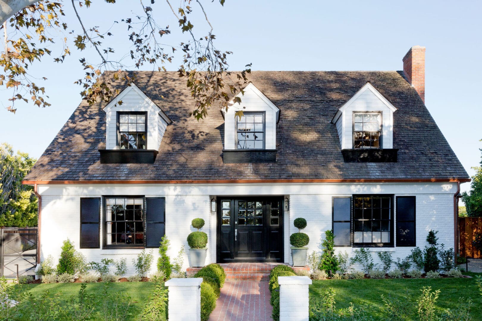 White house with dormer windows and garden.