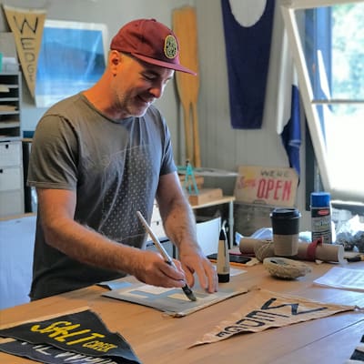 Man painting banner in workshop.