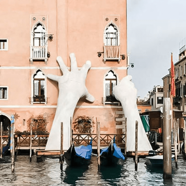Large hands sculpture on building facade, Venice.