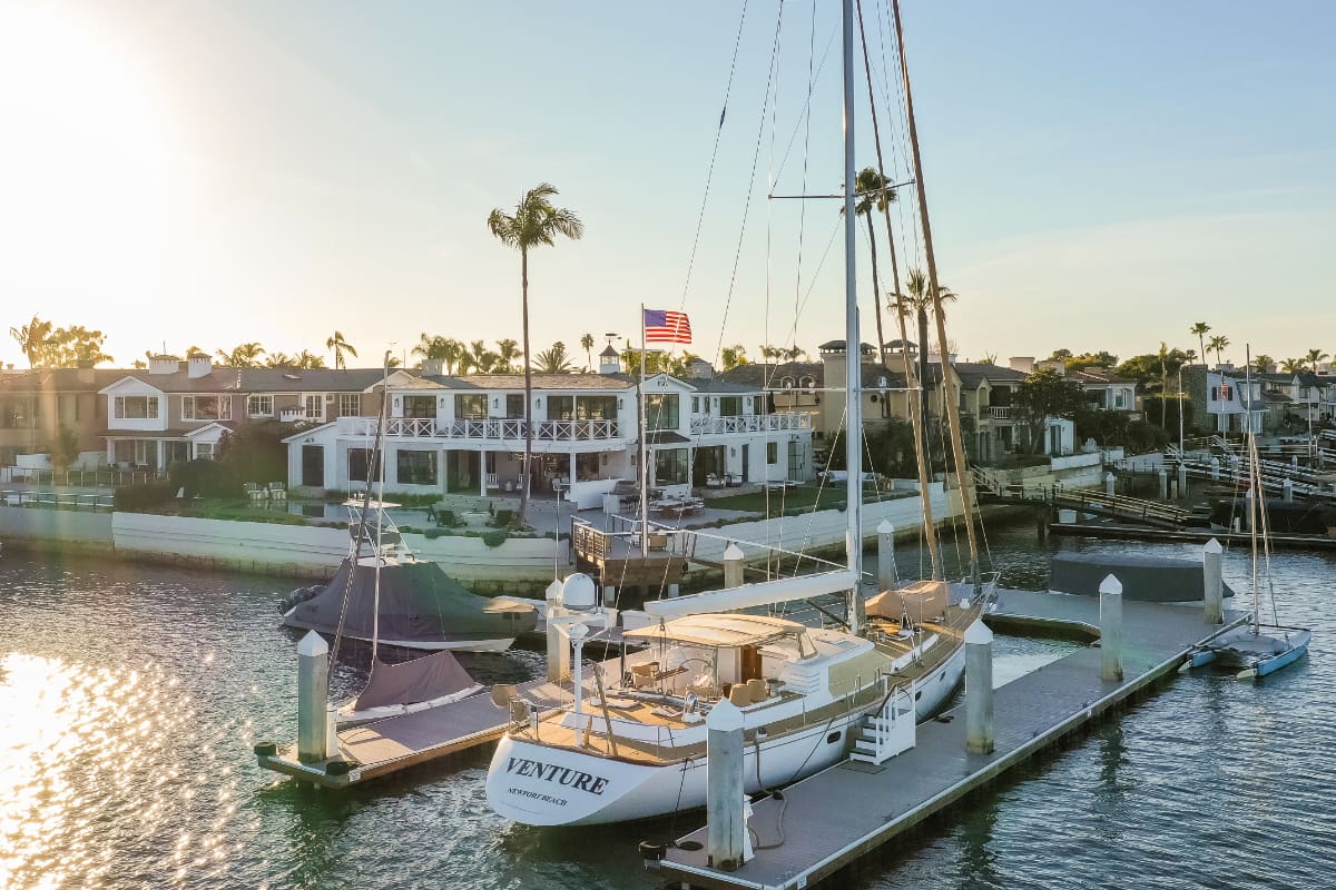 Boat docked by waterfront homes at sunset.