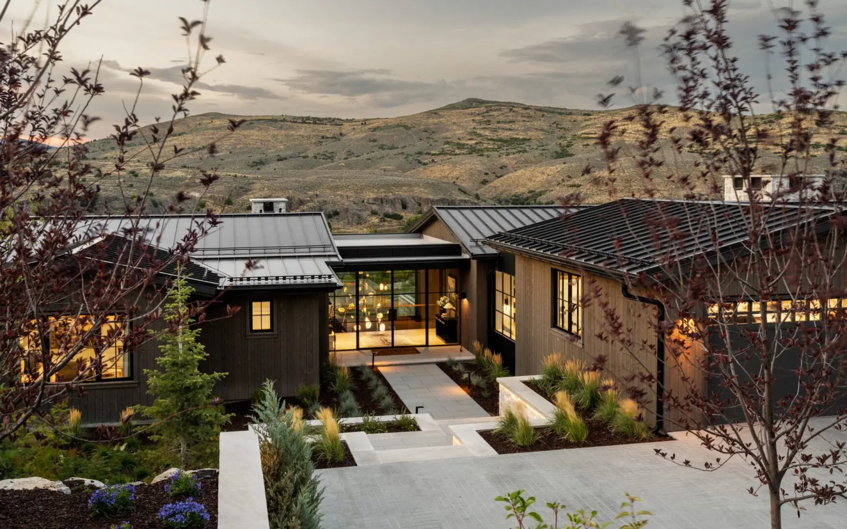 Luxury mountain home with wood siding and large glass doors.