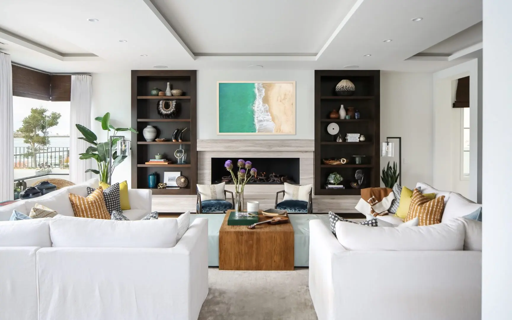 Coastal living room with beach art and white sectional sofas.