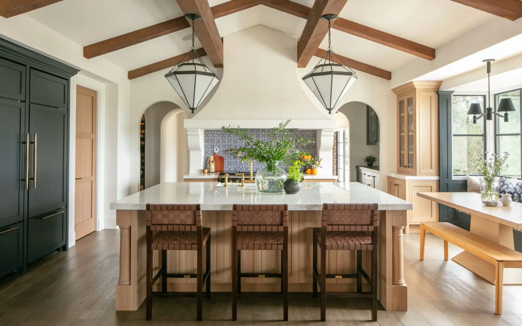 Modern Spanish kitchen with wood beams and two-tone cabinetry.