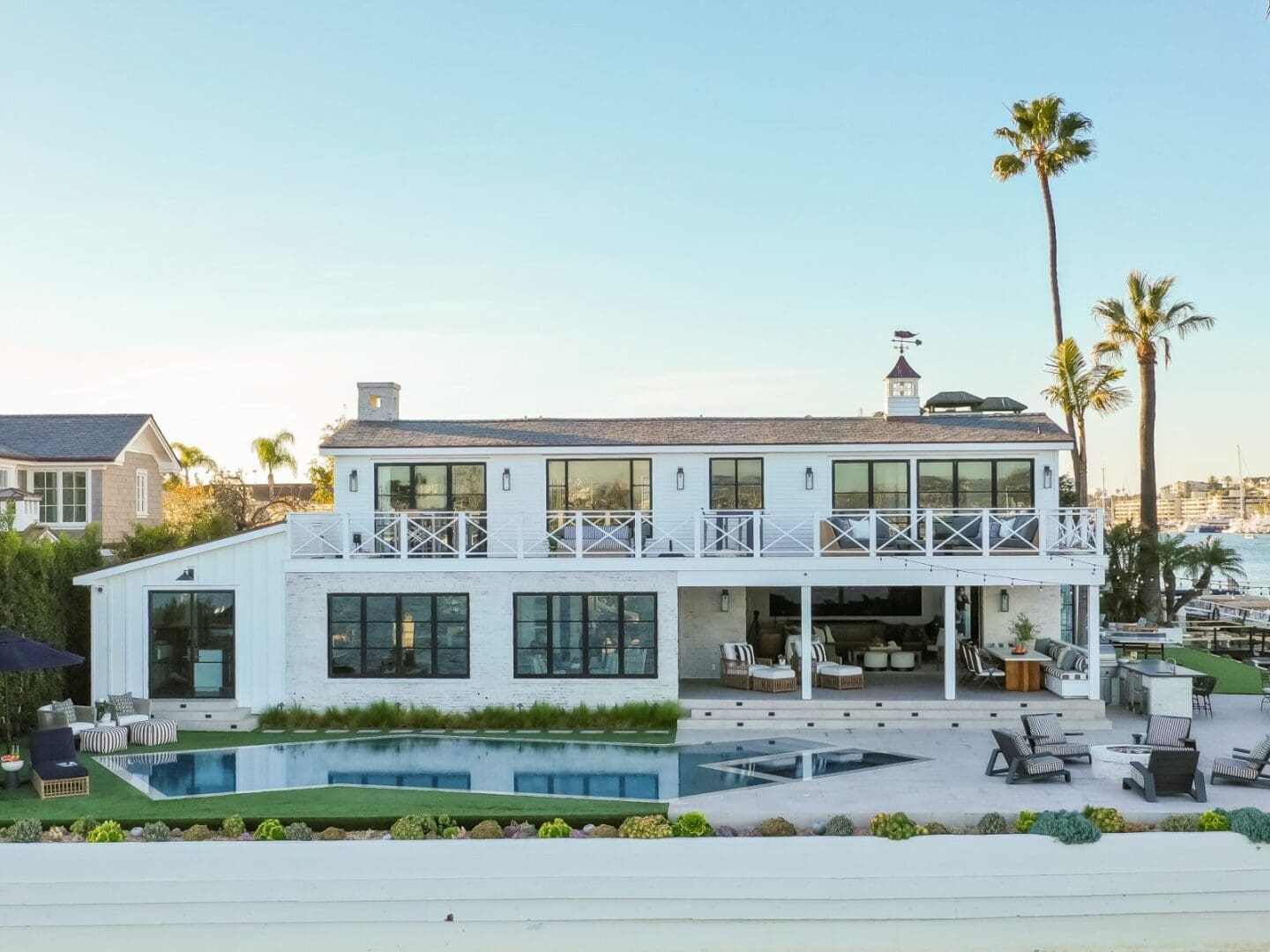 White beach house with palm trees on the bay in Newport Harbor.
