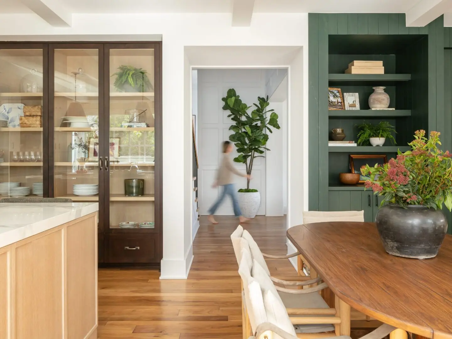 A girl walking between a kitchen and dining room.