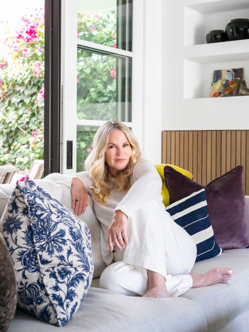 WENDY-BLACKBAND-WEBSITE-2020 Blackband Design owner and principal designer, Wendy Blackband, sitting on a white sofa in her home.