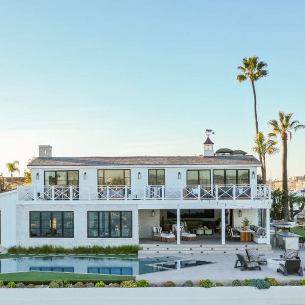 White beach house on the water with palm trees.