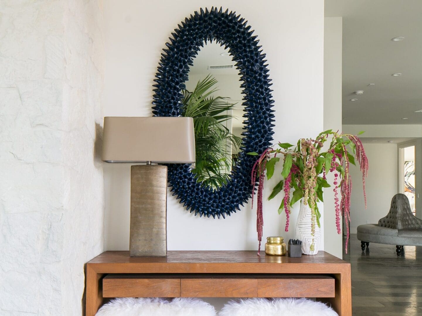 Navy spiky mirror with gold lamp on a wooden console table.