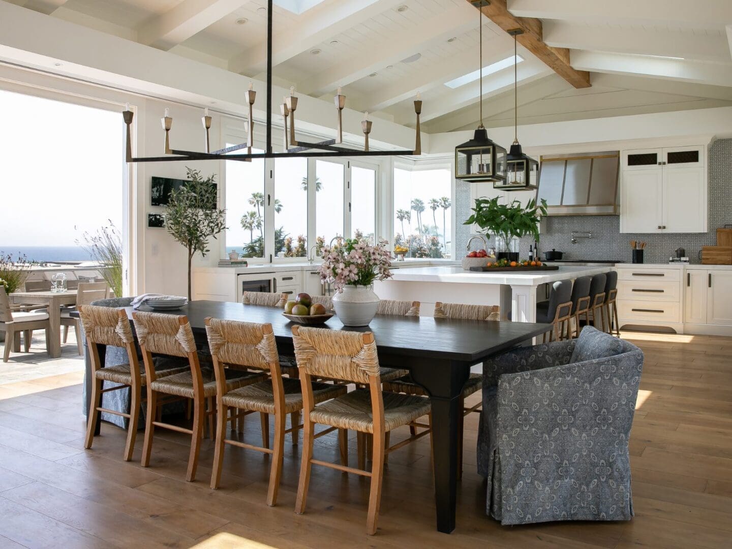 Coastal dining room with rattan chairs and iron chandelier.