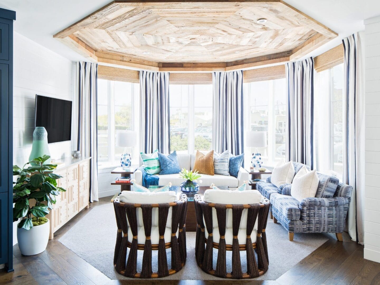 Coastal living room with woven accent chairs and striped window treatments.