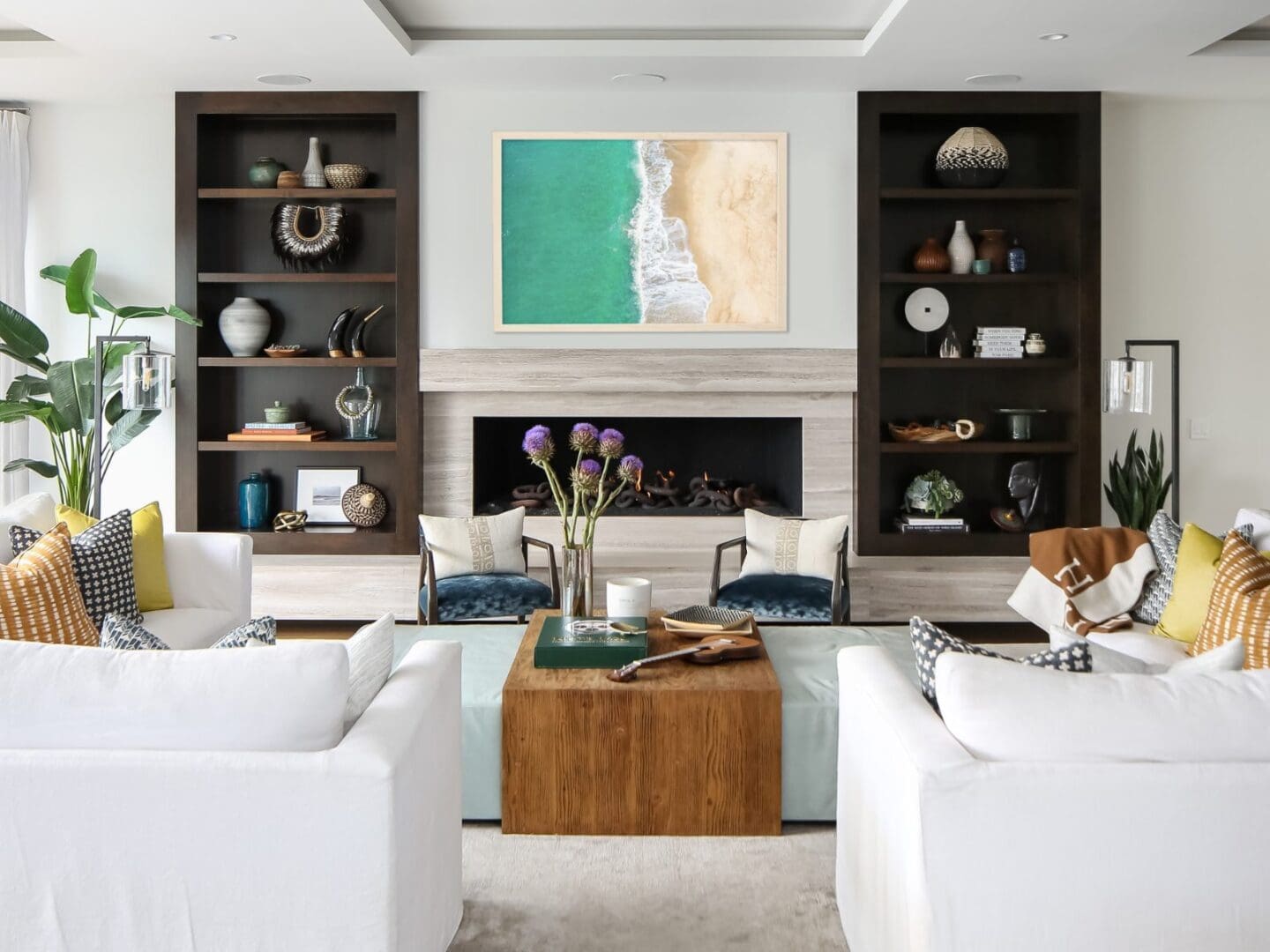 Coastal living room with white sectional sofas and built-in shelves.