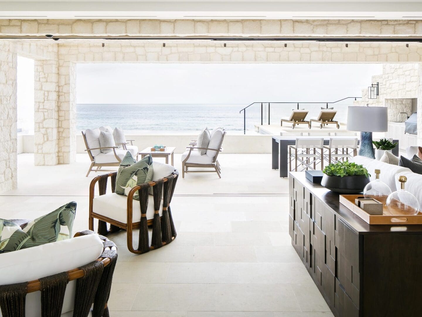 Coastal lounge with rattan furniture and palm leaf pillows.