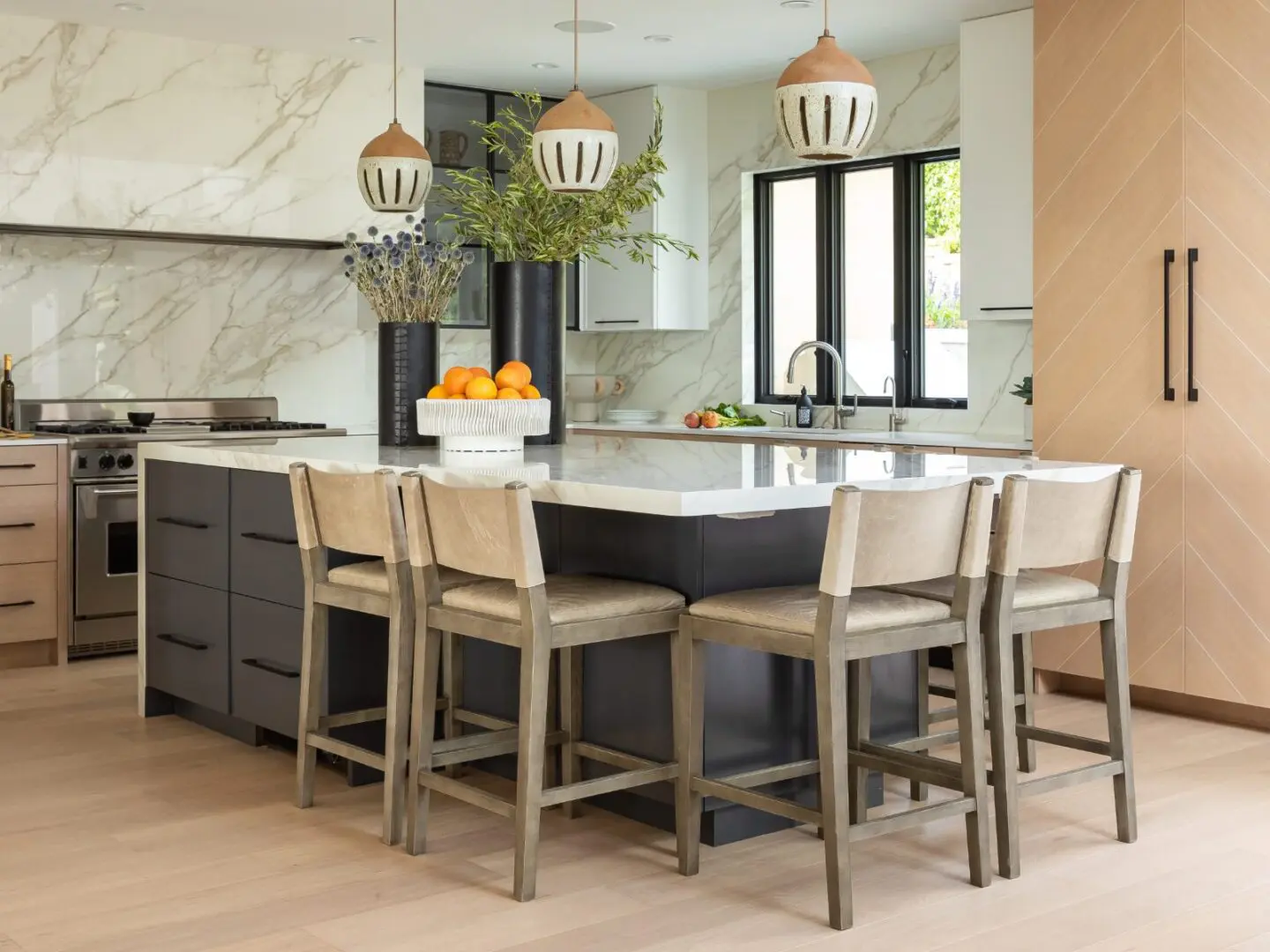Luxury kitchen with marble slabs and ceramic pendants.