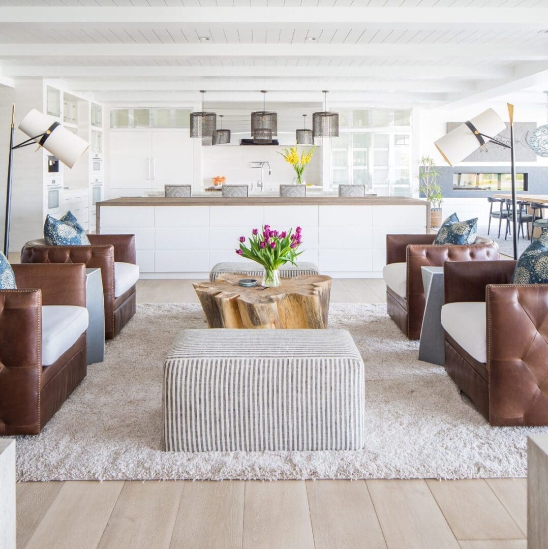 Open floor plan modern beach house with leather chairs and white kitchen.