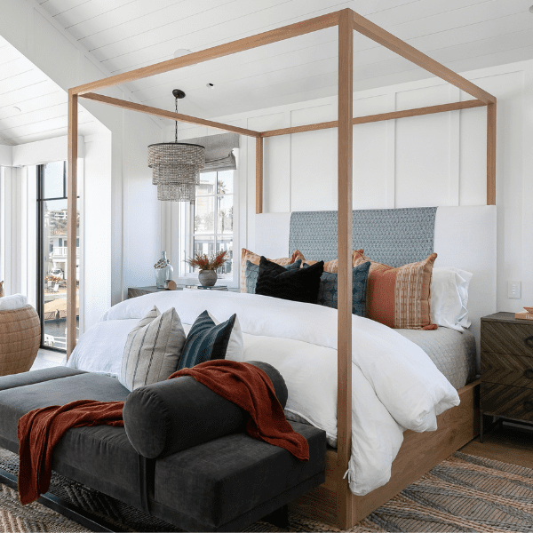 Canopy bed with white linen duvet and suede bench.