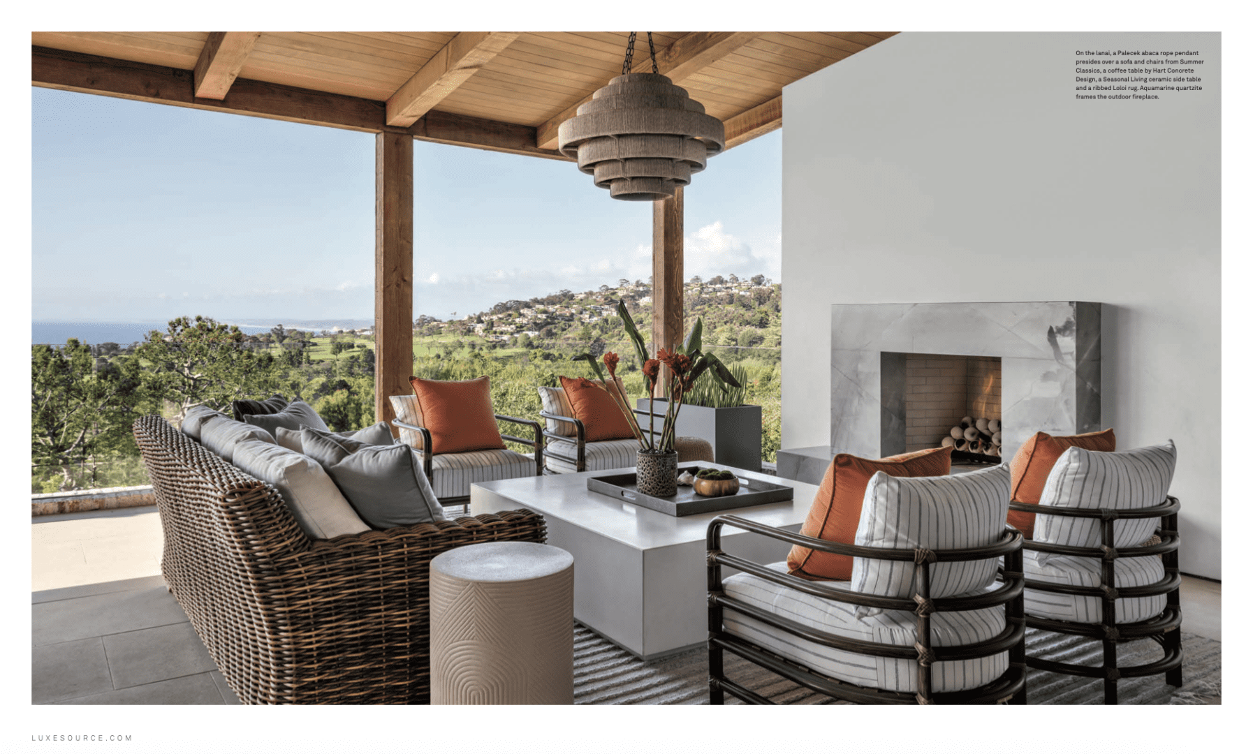Warm-toned outdoor furniture with fireplace on patio overlooking La Jolla.