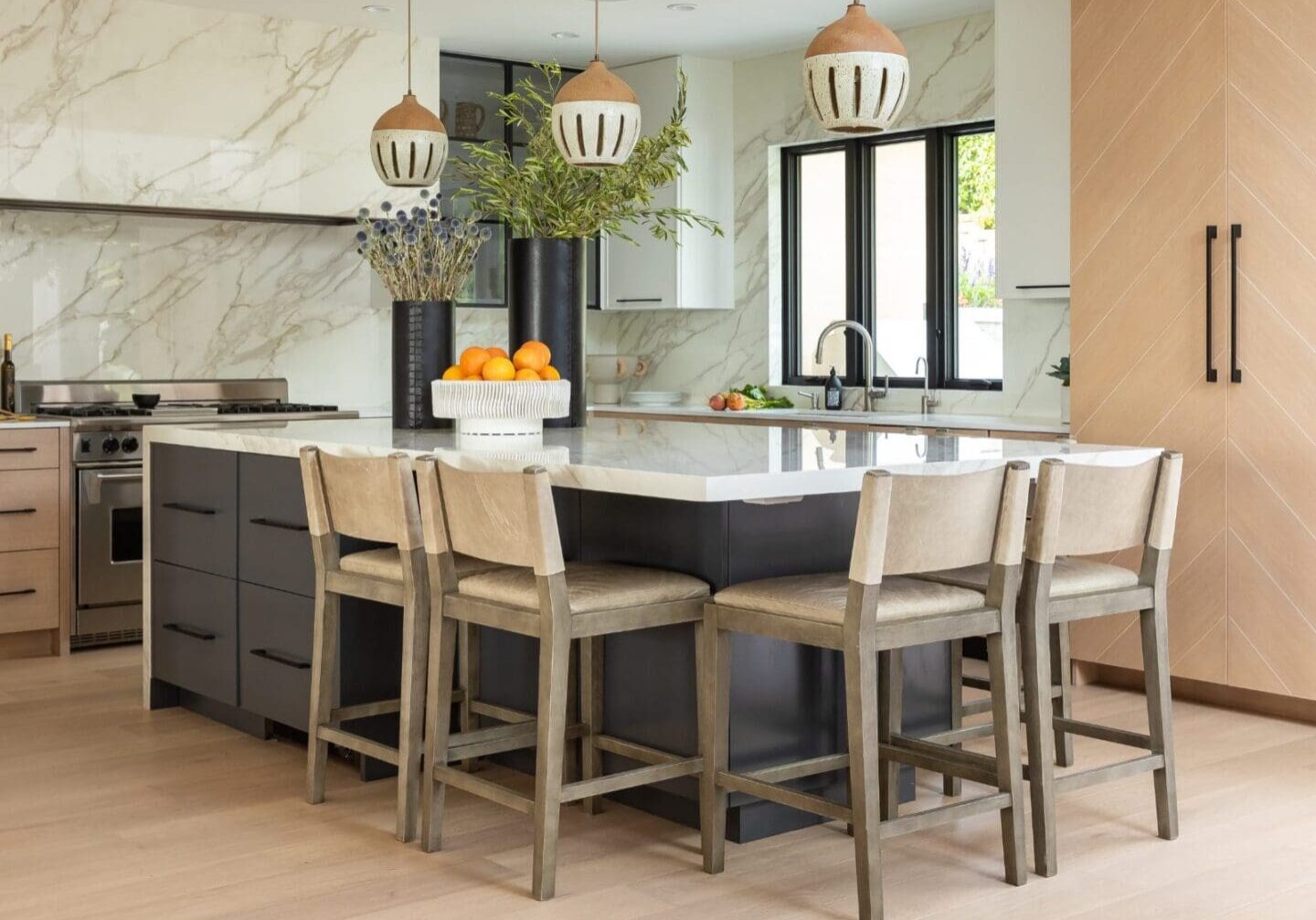 Luxury kitchen with marble slabs and ceramic pendants.