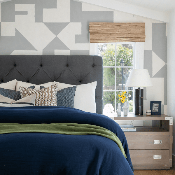 Guest bedroom with patterned wallpaper and upholstered bed.