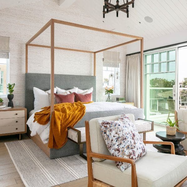 Canopy bed with pink pillows and a mustard linen throw blanket.